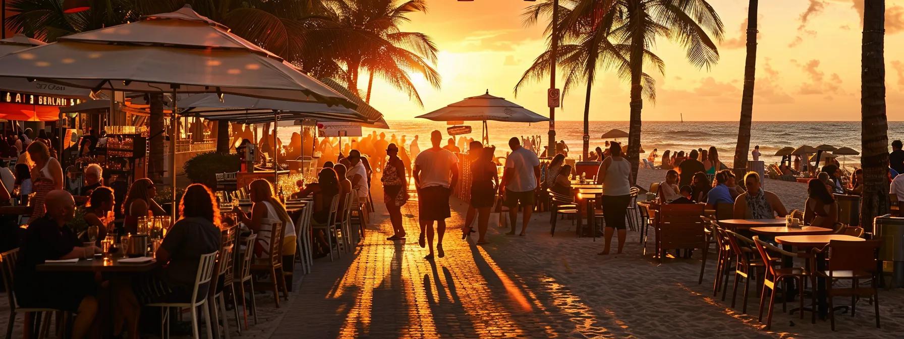 a vibrant outdoor dining scene on hollywood beach showcases elegantly set tables under stylish umbrellas, with guests enjoying gourmet dishes while a picturesque sunset bathes the atmosphere in warm hues.