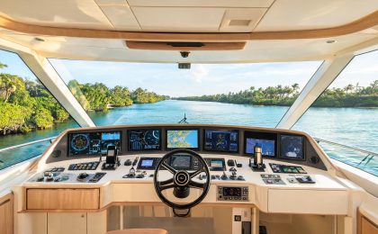 Professional yacht captain in uniform standing at the helm of a large motoryacht navigating Fort Lauderdale's Intracoastal Waterway on a clear day